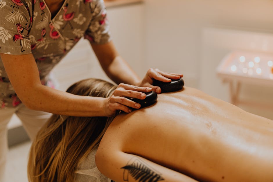 Spa therapist performing hot stone massage technique on client's back